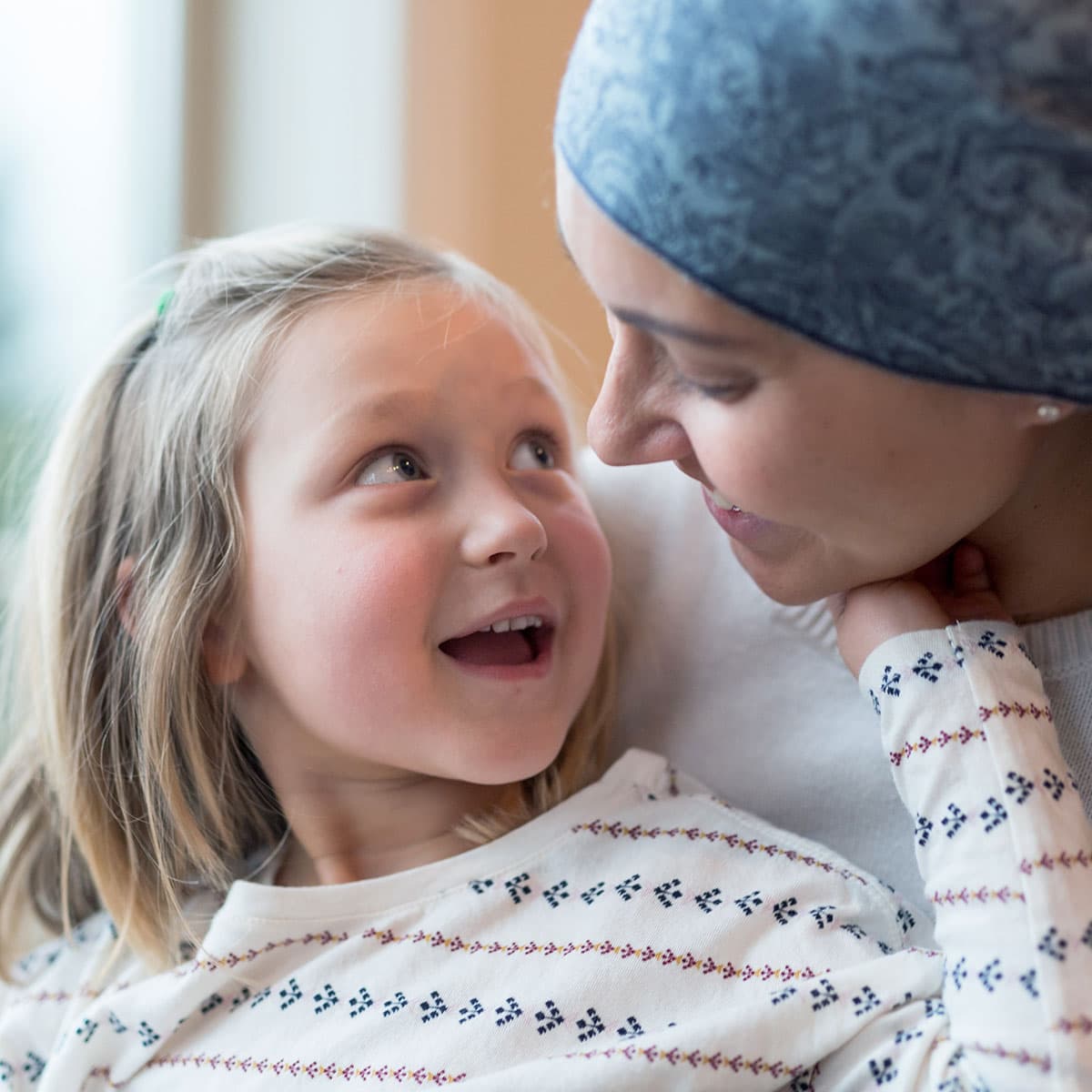 Woman with cancer is hugging her daughter.