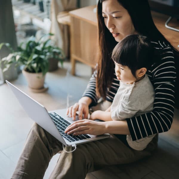 Small business owner working from home with her child on her lap.