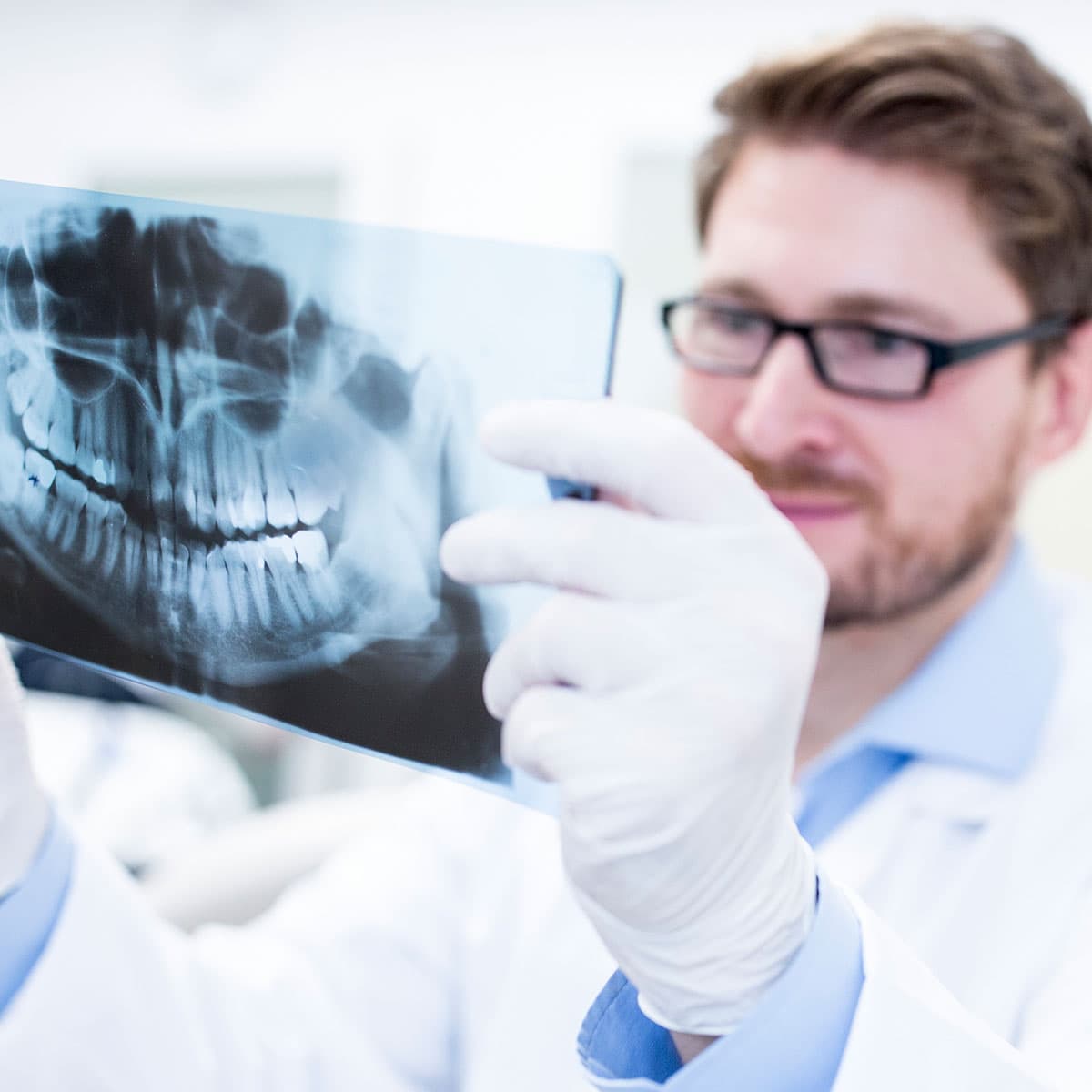 A dentist looking at a set of teeth x-ray/.