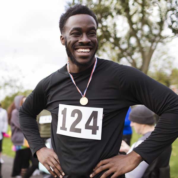 Man smiles with a medal around his neck after finishing a race..