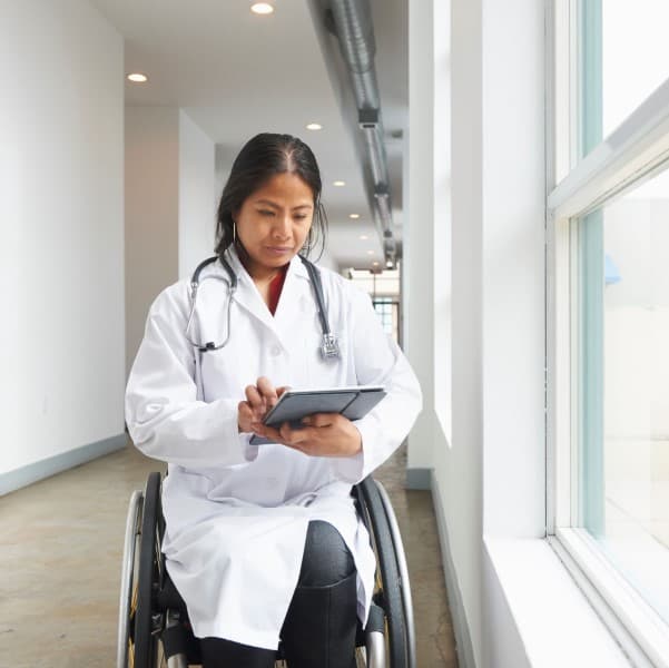 Female doctor in wheelchair looking at a tablet.