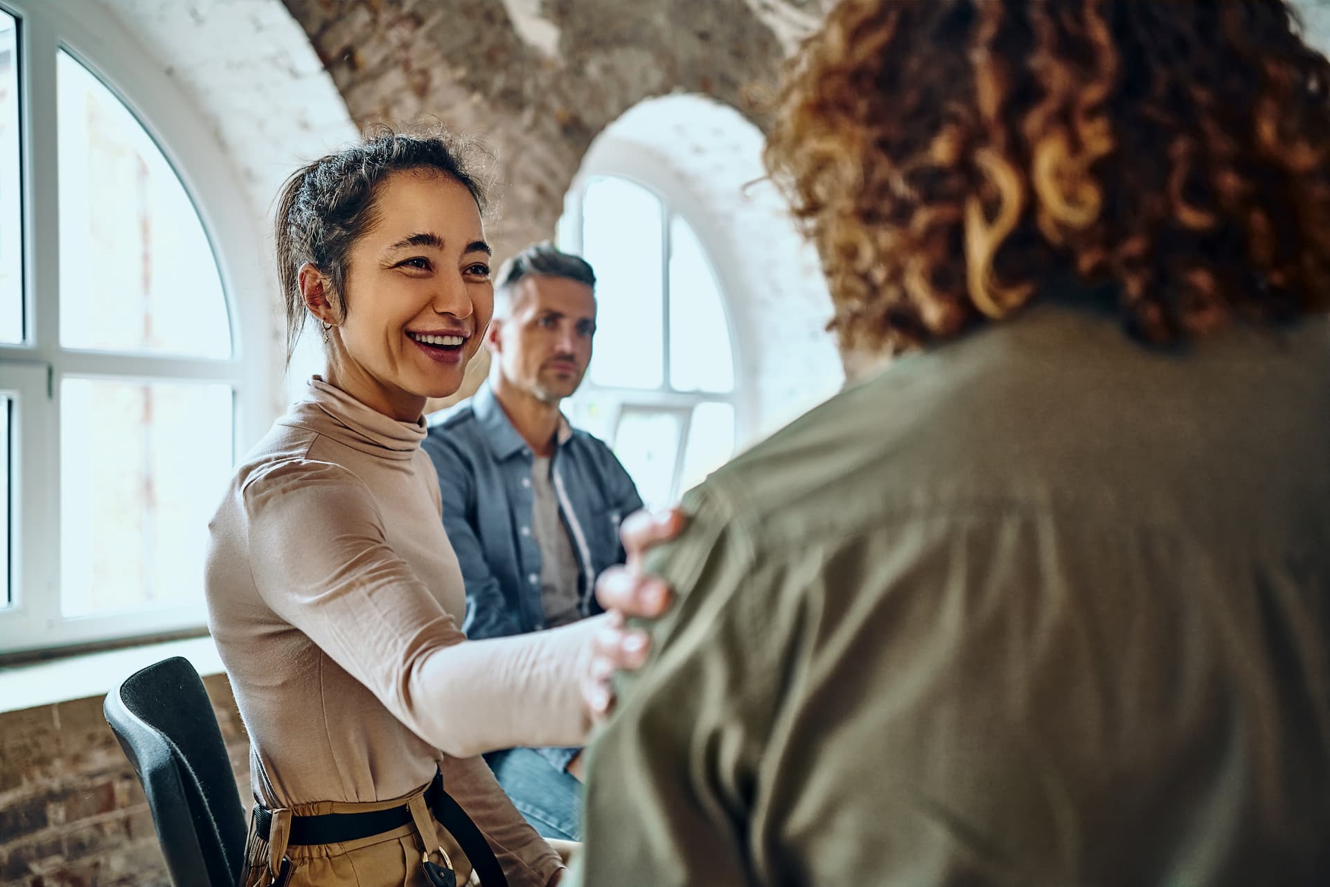 A woman smiling to a man and placing her hand on his shoulder