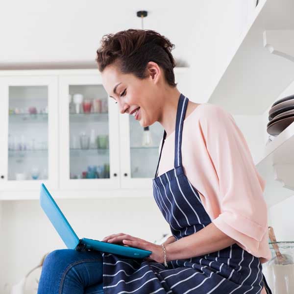 Woman business owner in an apron looks at laptop..