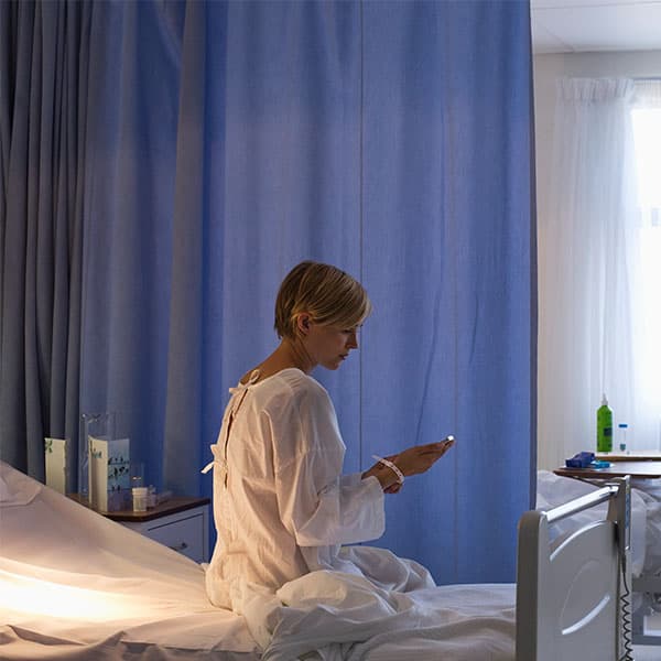 Middle aged woman sitting on hospital bed.