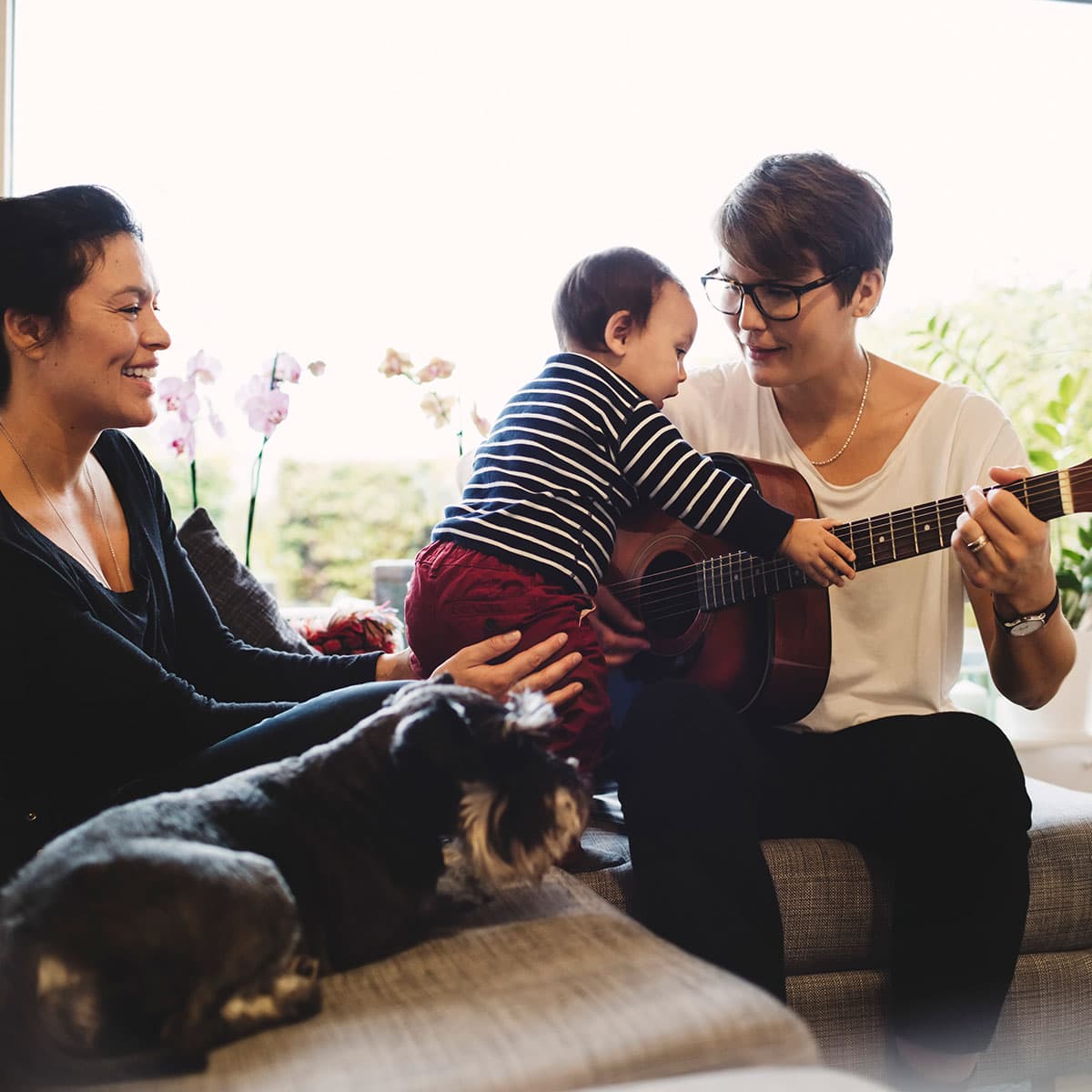 Lgbtq couple playing with their child on their couch.