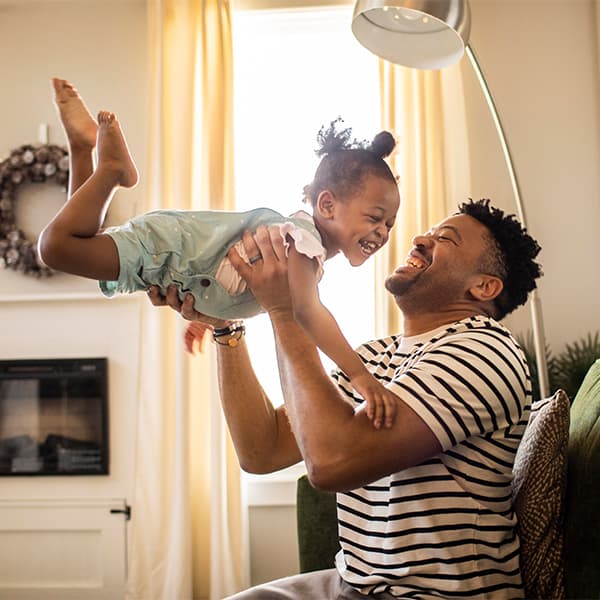 Father lifting his toddler daughter in the air.