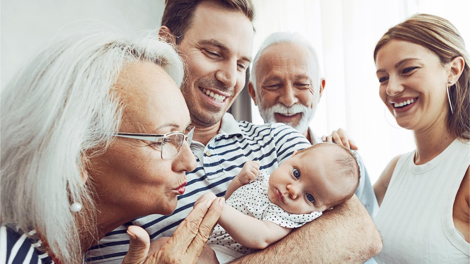 smiling-father-holding-baby-with-wife-and-parents-looking-on