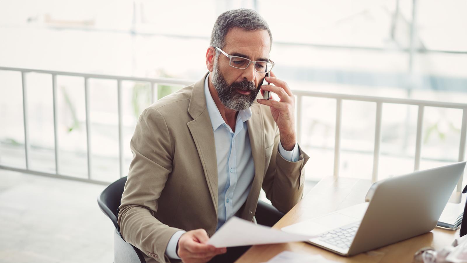 Man talking on his cell phone looking at paperwork