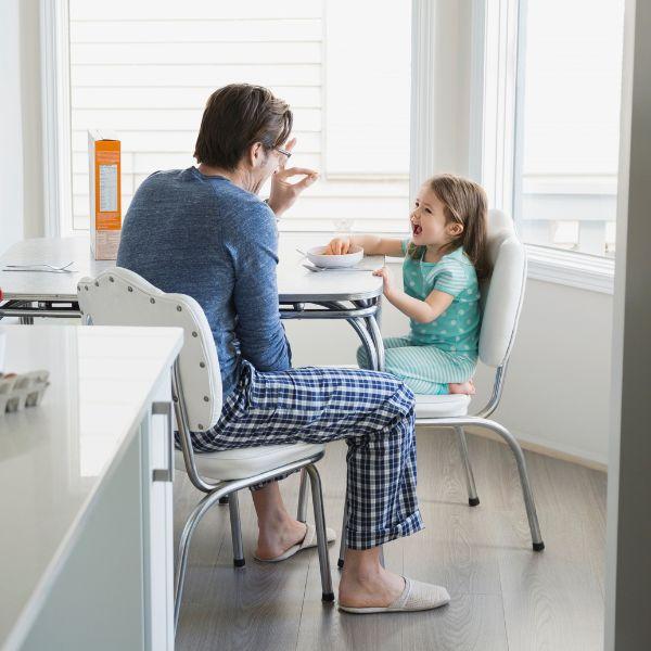 Father feeding daughter breakfast .