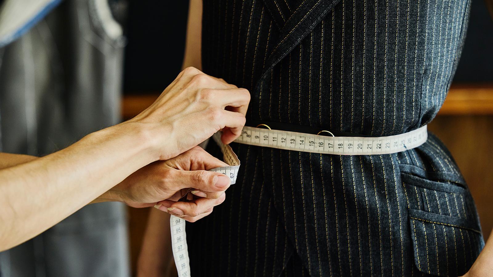 Tailor measuring waist with a measuring tape Tailor measuring waist with a measuring tape