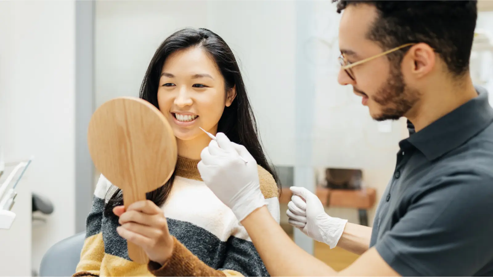 Patient holding a mirror for her dentist