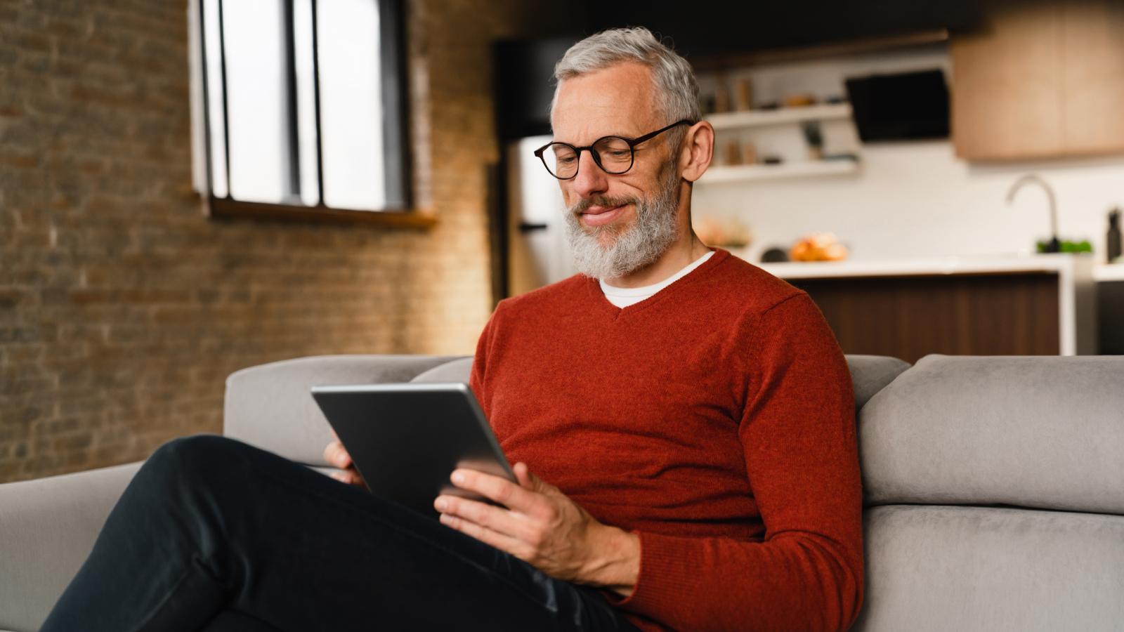 Man sitting on a couch looking at this tablet. Man sitting on a couch looking at this tablet.
