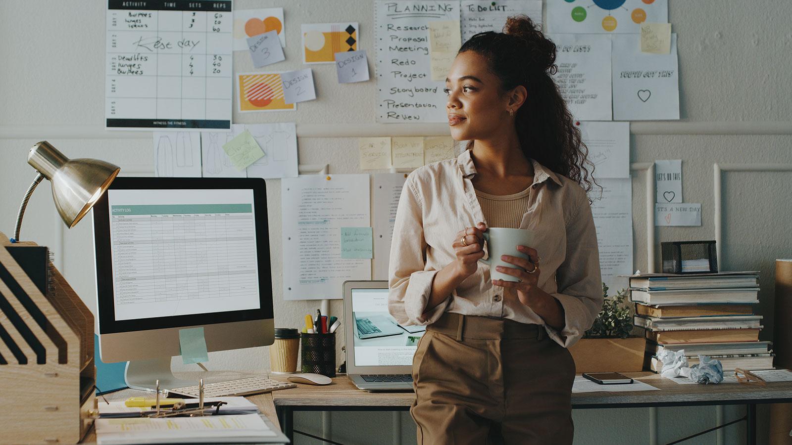 Business-woman-stands-and-holds-cup-of-coffee-in-her-home-office