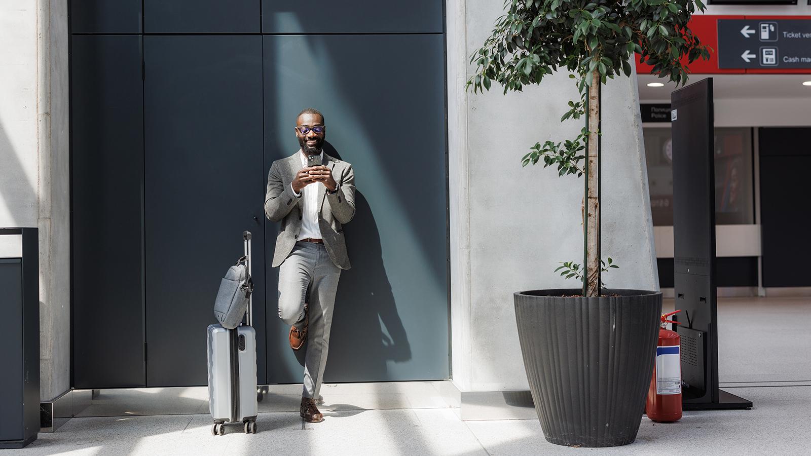 A professional standing by a wall and using phone A professional standing by a wall and using phone
