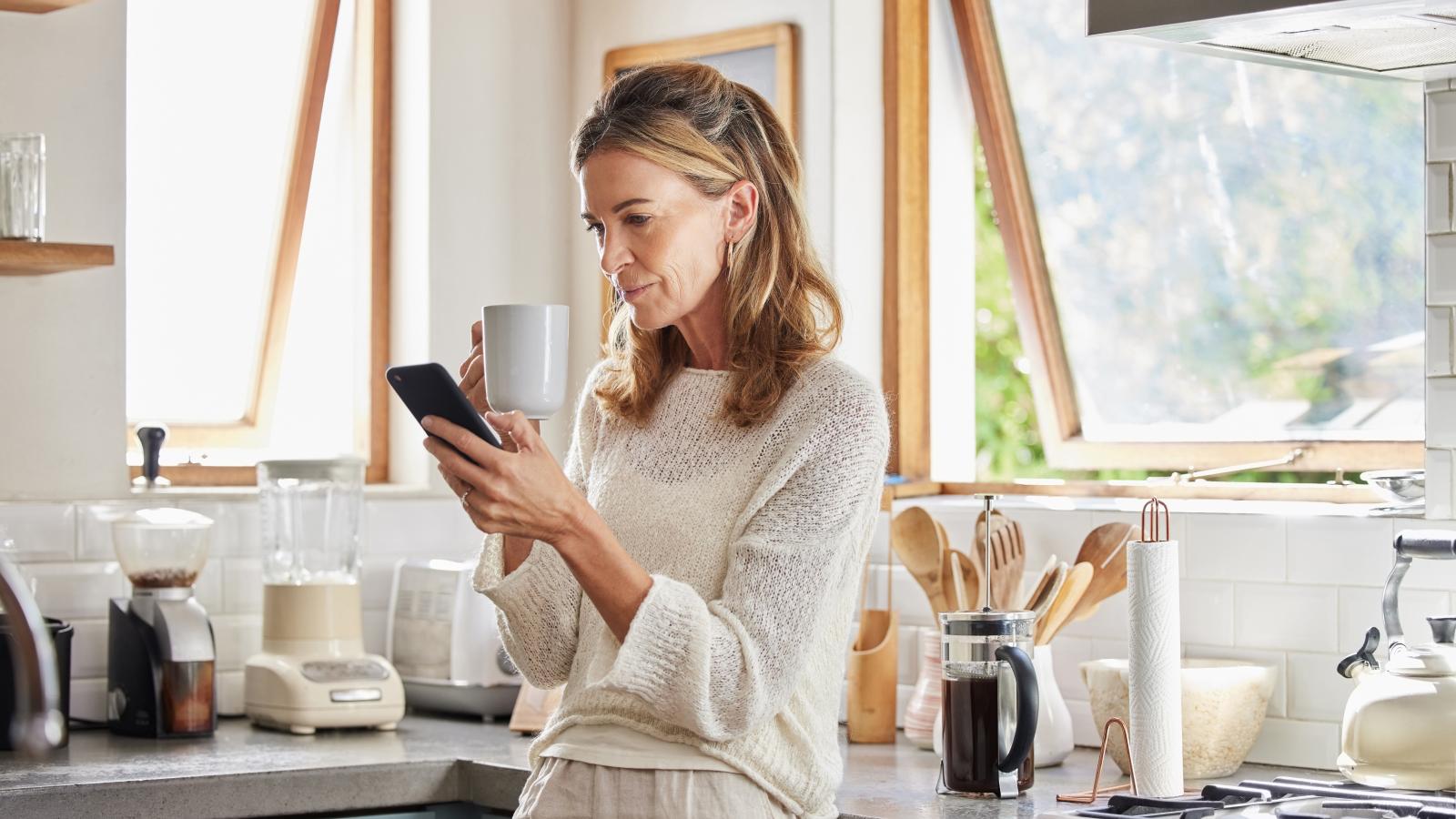 Woman using phone in kitchen