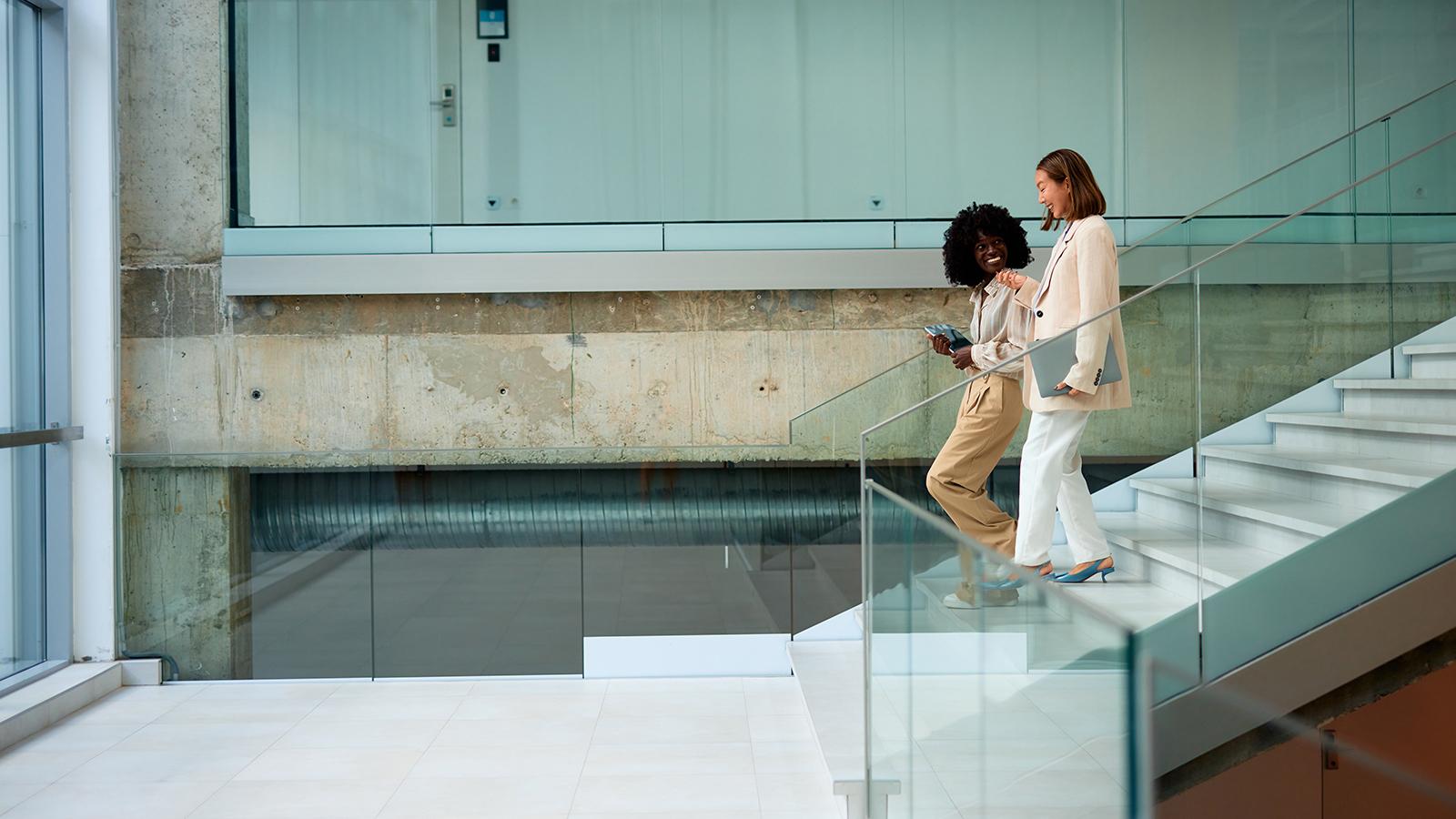 Two women moving down the stairs in office Two women moving down the stairs in office