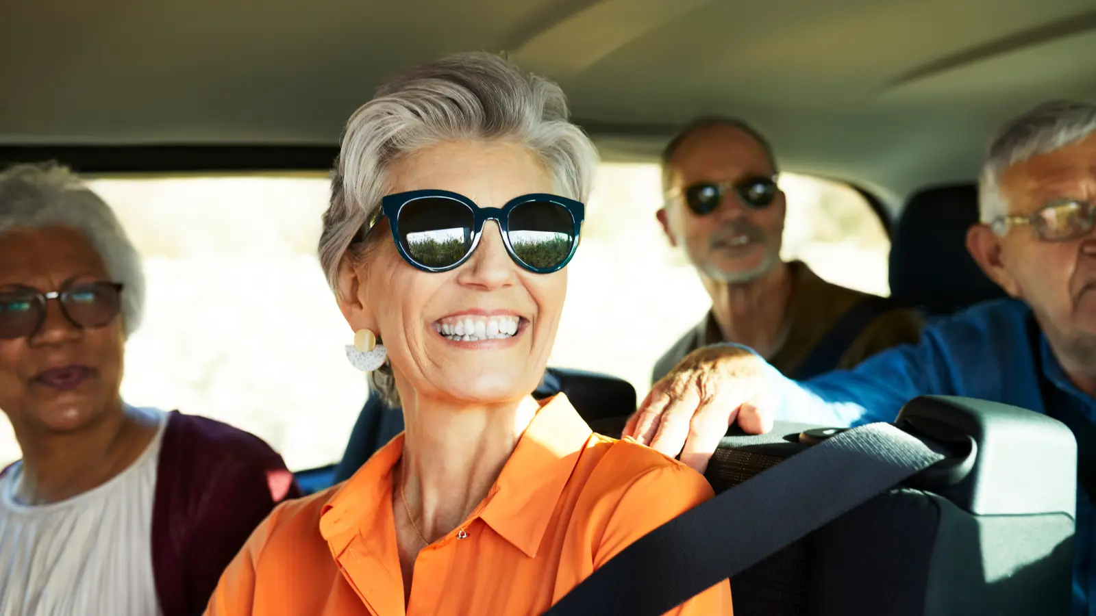 Mature adult friends smiling on a road trip together.