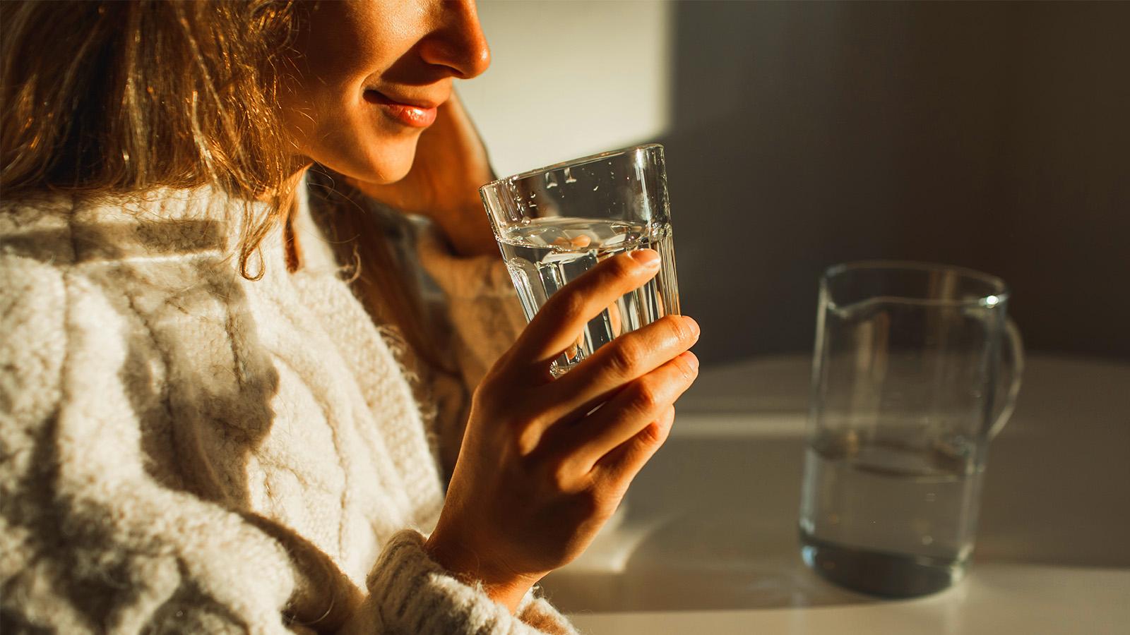 Woman holding a glass for a saltwater rinse for mouth