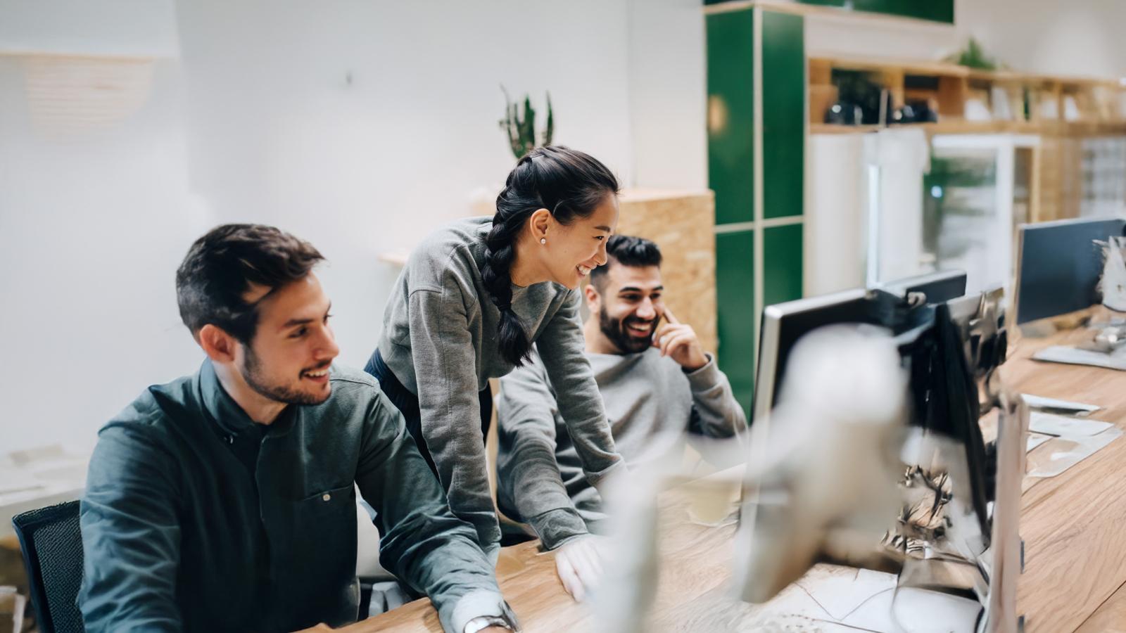 Colleagues smiling and looking at a computer together.