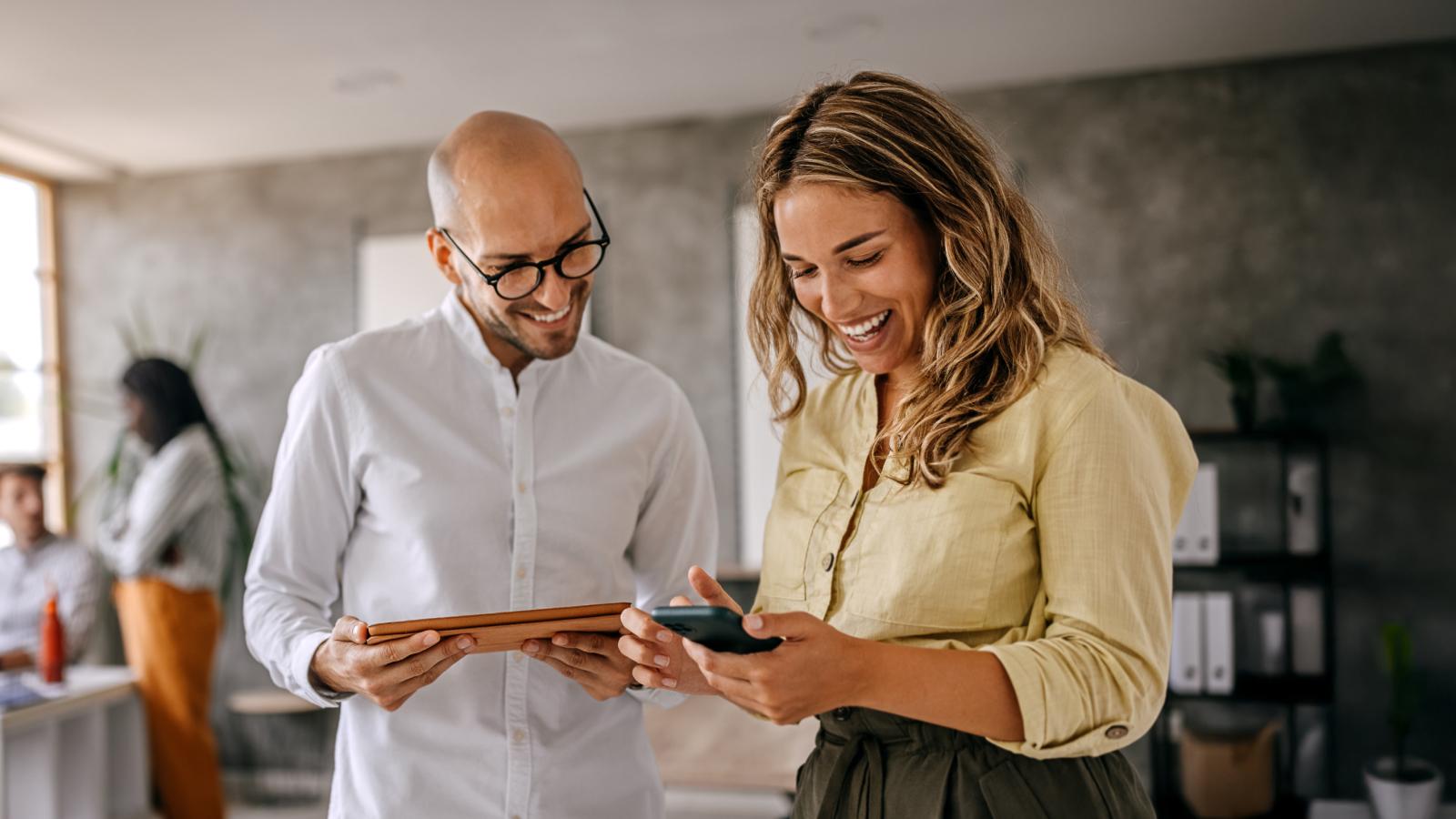 Businesswoman standing with colleague looking at smartphone